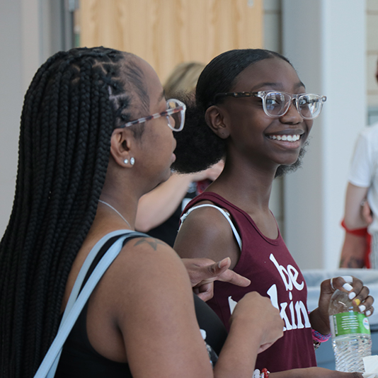  Two students stand together, one is smiling